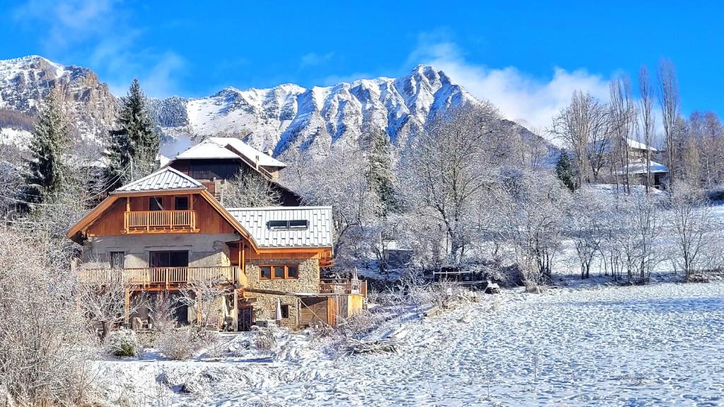 une cabane en rondins dans la neige avec des montagnes en arrière-plan dans l'établissement La Mélézière-Cimes-Appartement Grand Confort 120m2 6 personnes, aux Orres