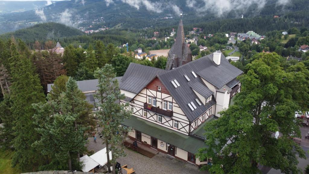 Aerial view of half-timbered hotel building and church steeple surrounded by trees and hillside town.