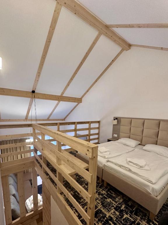 Cozy mezzanine bedroom with twin beds, wooden railing, exposed beams, and vaulted white ceiling.