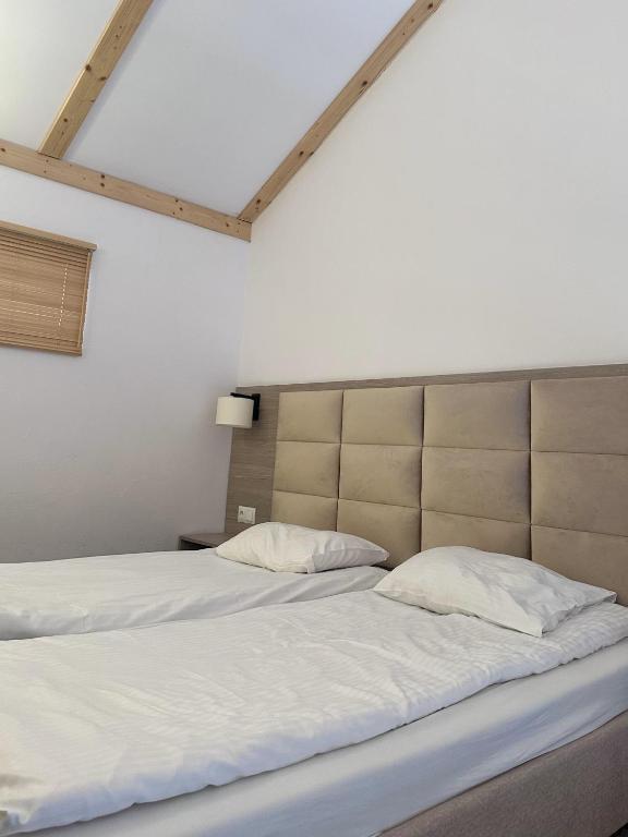 Bright bedroom with two single beds, padded headboard, bedside lamp, and high angled ceiling.