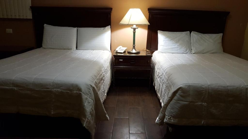 una habitación de hotel con 2 camas y una lámpara en una mesa en Hotel La Posta, en Monclova