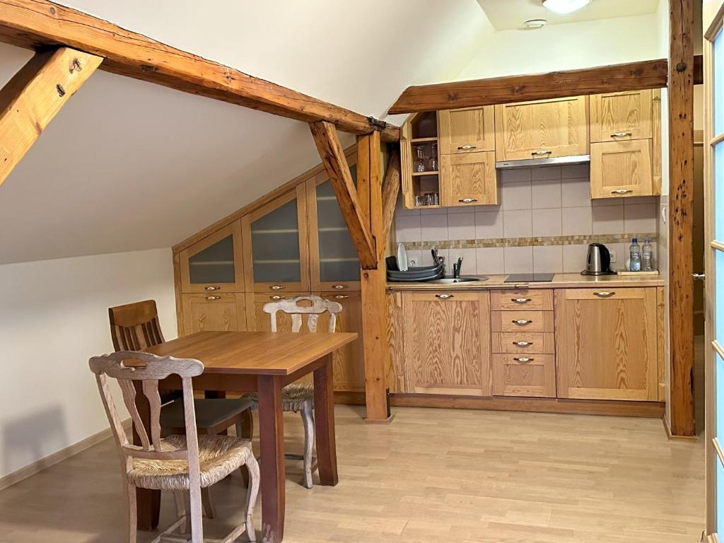 Compact attic kitchen and dining nook with wooden cabinets, table, chairs and visible ceiling beams