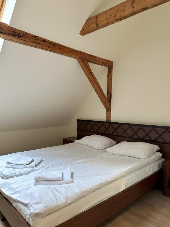 Double bed under sloped ceiling with exposed beams, neatly folded towels on white linens