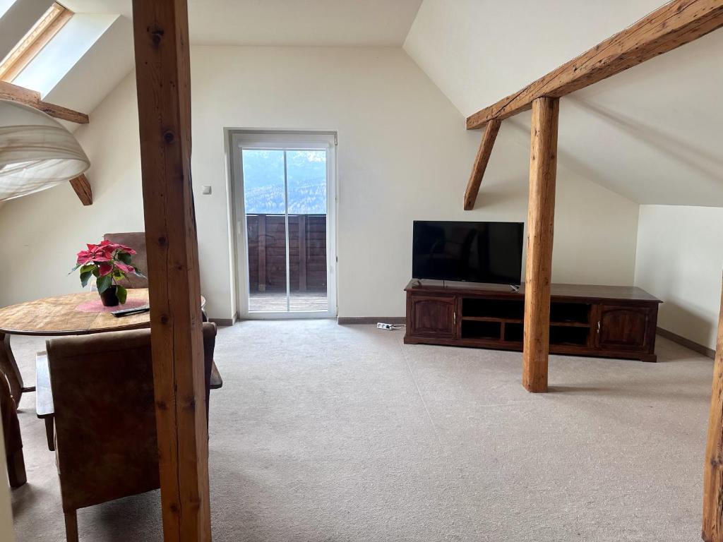 Bright loft living room with TV, sliding balcony door, wooden beams and round table with potted plant