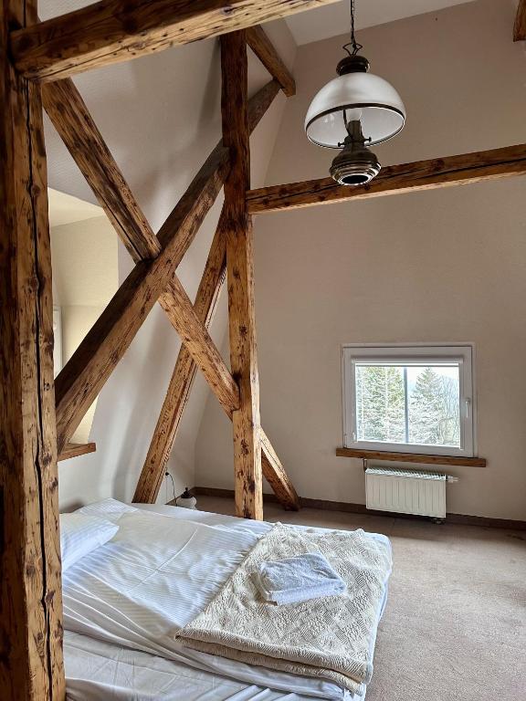 Rustic bedroom with low bed, exposed wooden beams, small window and folded towels on blanket