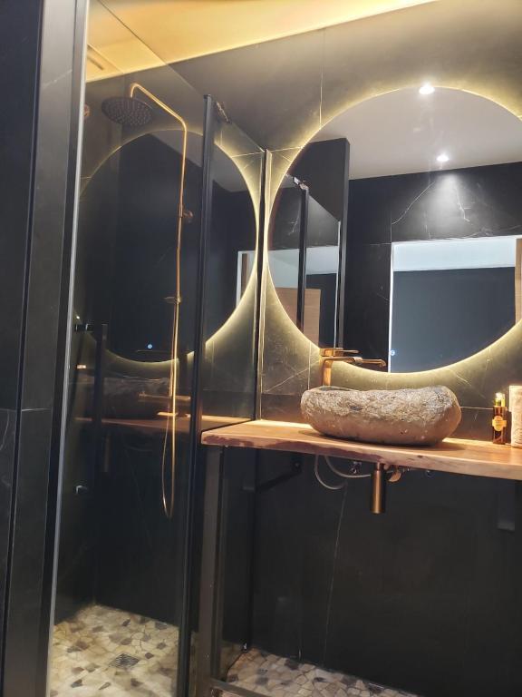 La salle de bains est pourvue d'un miroir rond sur une étagère. dans l'établissement Agréable maison bien située, à Capbreton