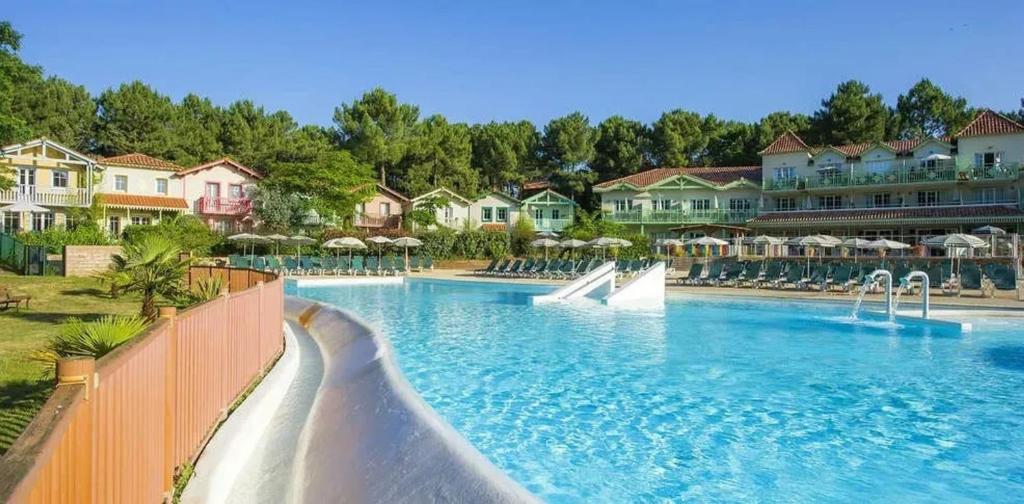 une piscine dans un complexe hôtelier avec un toboggan aquatique dans l'établissement Maison charmante à Lacanau avec piscine partagée et terrasse, à Lacanau
