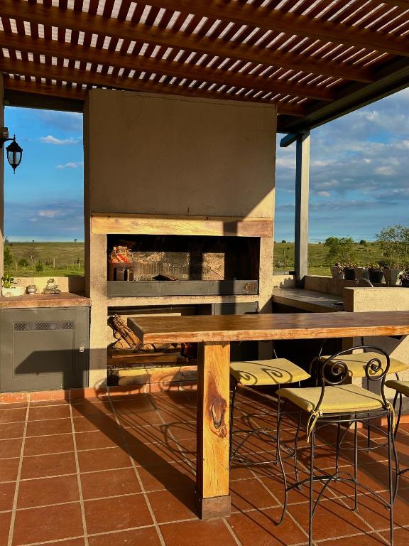 a outdoor kitchen with a grill and a table and chairs at Cabañas Casa Flor Yacanto in Villa Yacanto