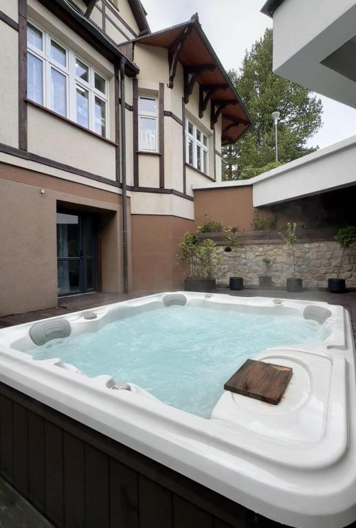 Outdoor bubbling hot tub in courtyard beside timber-trimmed building, relaxed daytime setting.