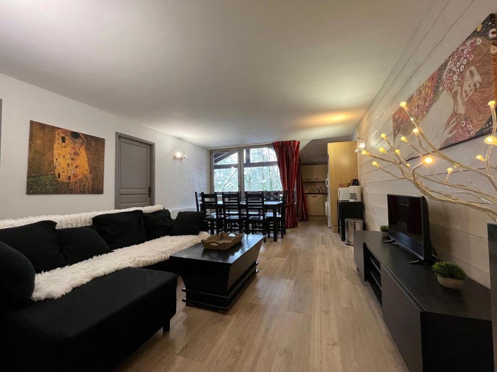 un salon avec un canapé noir et une télévision dans l'établissement Appartement spacieux 8 pers avec balcon, parking et WiFi, proche centre et thermes - FR-1-512-214, à Brides-les-Bains
