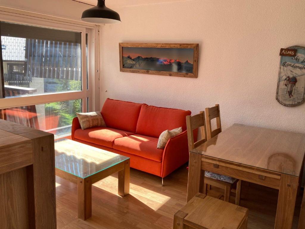 un salon avec un canapé rouge et une table dans l'établissement Appartement accueillant au pied des pistes avec balcon et cuisine équipée - FR-1-516-21, à Les Deux Alpes