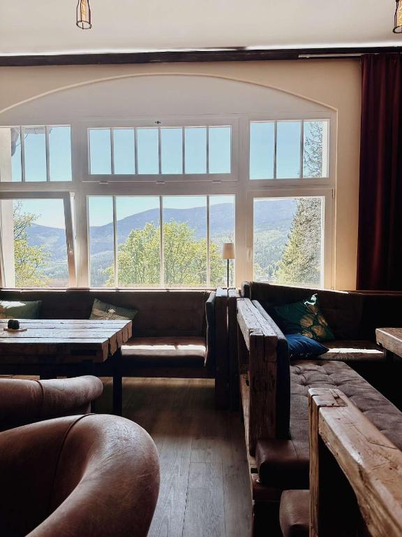 Cozy lounge with rustic wooden benches facing large window framing distant mountains and trees.