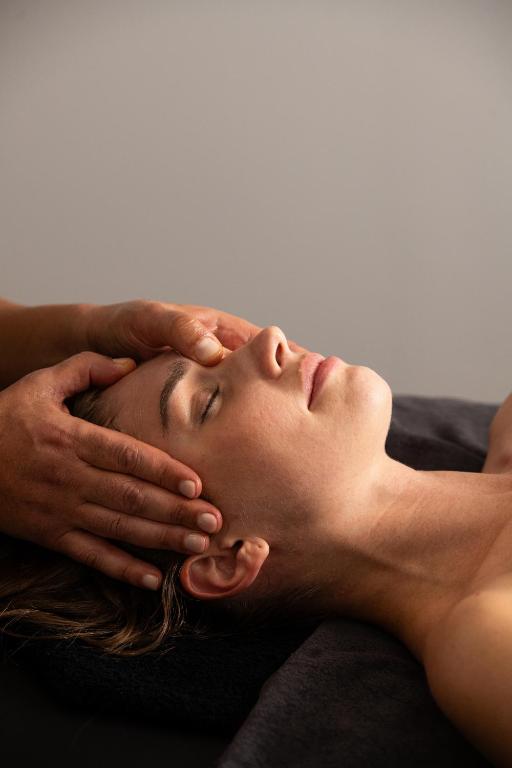 a woman laying on a bed with her hands on her face at Athenian Riviera Hotel& Suites in Athens