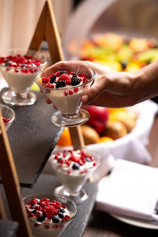 a person is reaching for a dessert in martini glasses at Athenian Riviera Hotel& Suites in Athens