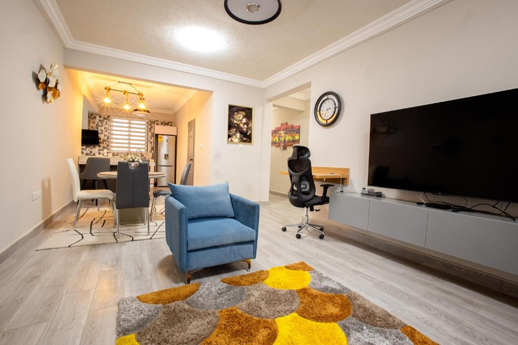 a living room with a large television and a blue chair at K's Place in Accra