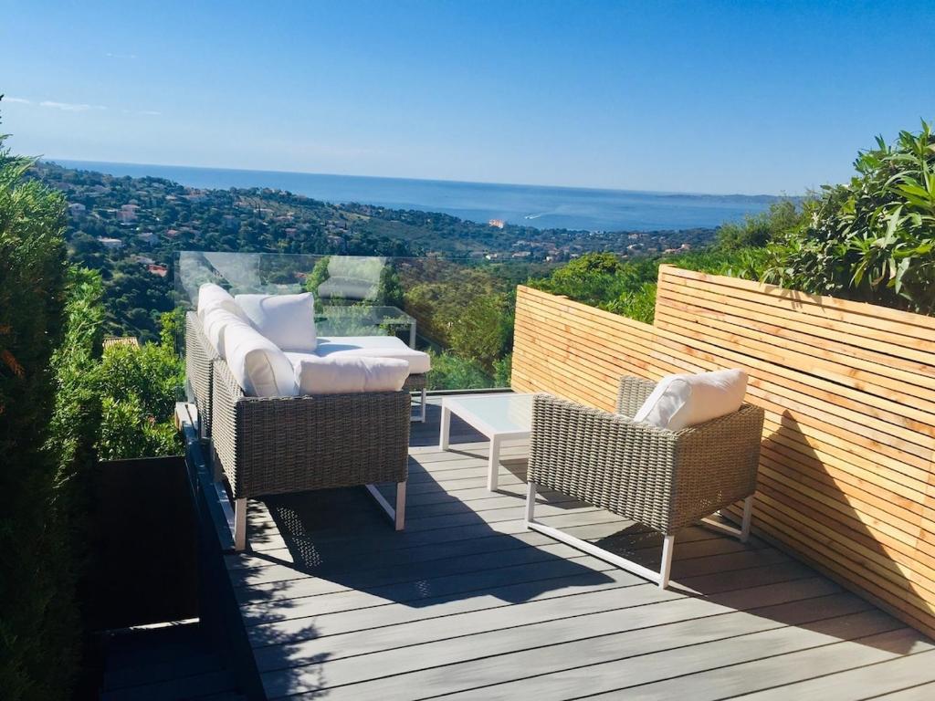 une terrasse avec deux chaises en osier et une table dans l'établissement Mazet moderne, vue mer, clim, piscine, à Roquebrune-sur Argens
