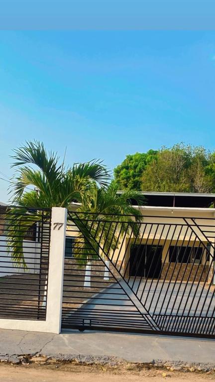 a gate with a palm tree in front of a building at Casa de Temporada em Iranduba in Iranduba