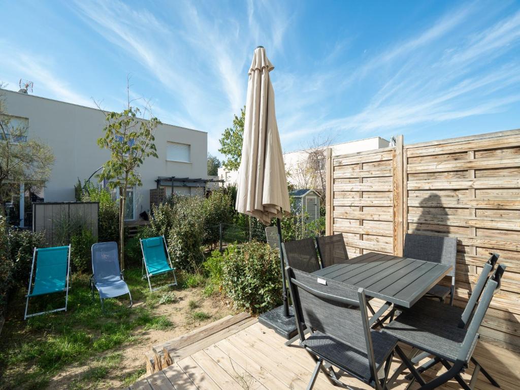 un patio avec une table, un parasol et des chaises dans l'établissement La Dune N 53 - Villa 3P6, à Sérignan