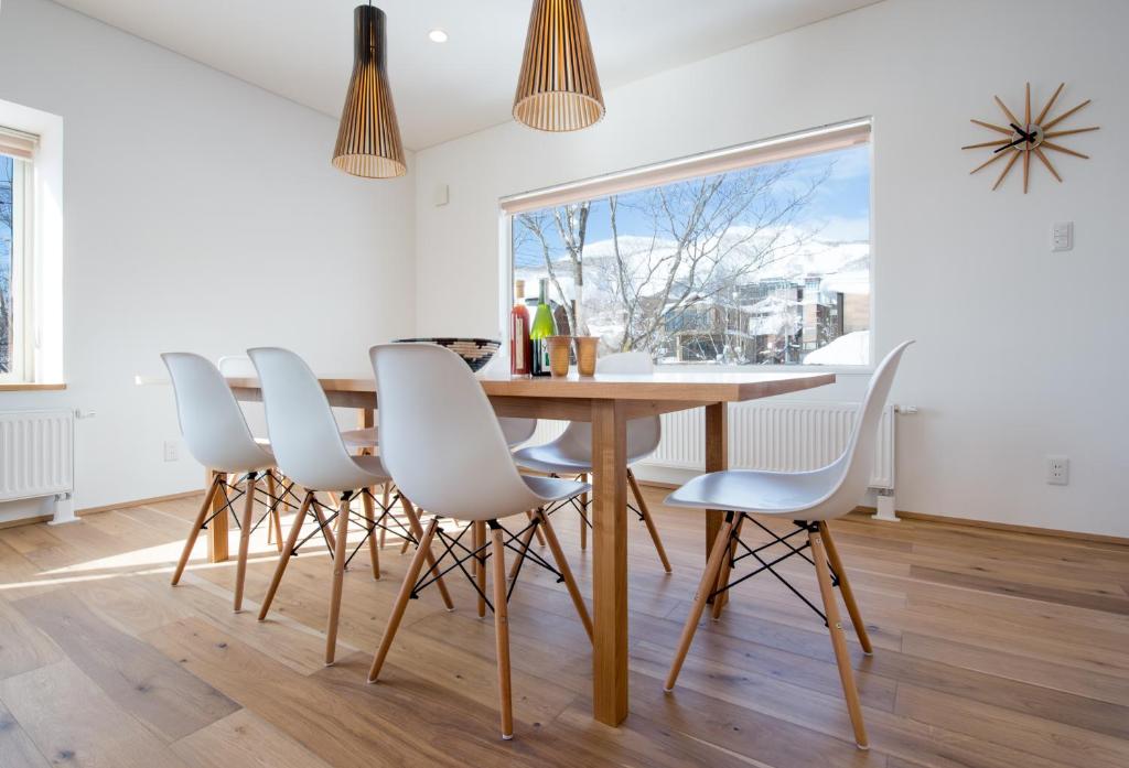a dining room with a wooden table and white chairs at Yuzuki in Niseko