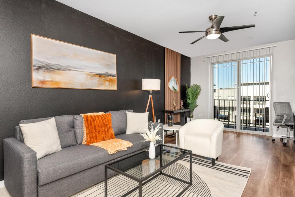 a living room with a gray couch and a ceiling fan at Sleek 2BR-Spring Training! w Pool, Gym&Parking in Tempe