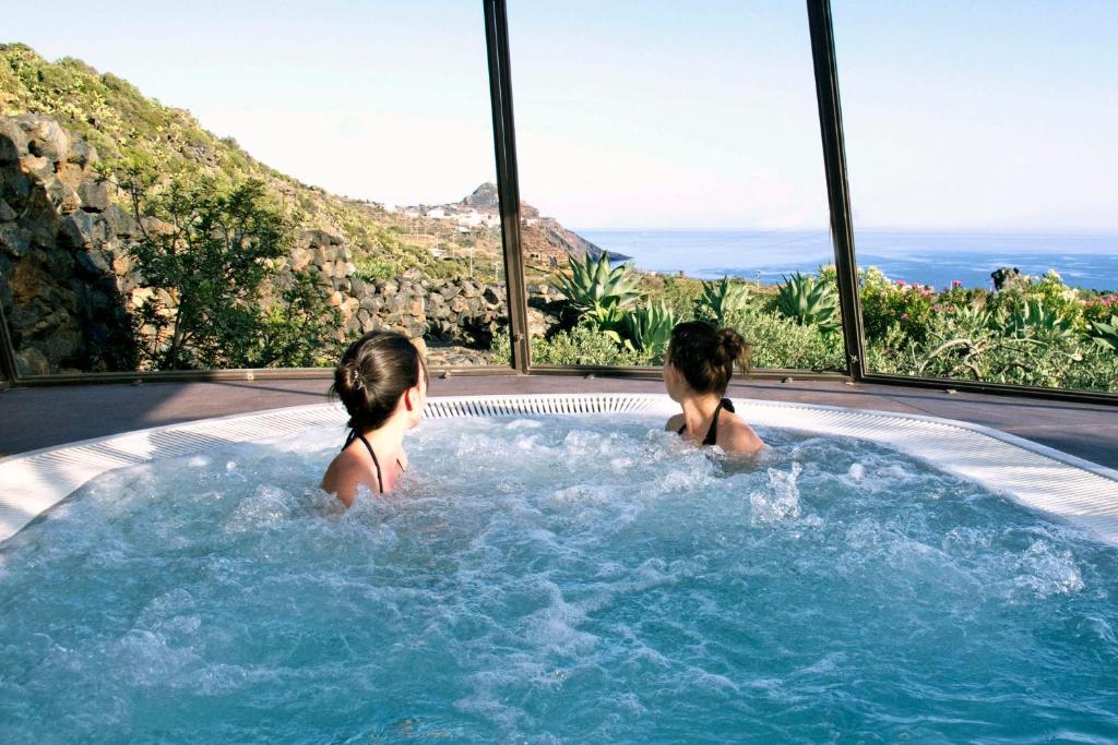 Due ragazze sono sedute in una vasca idromassaggio di Dammusi Sciuvechi a Pantelleria