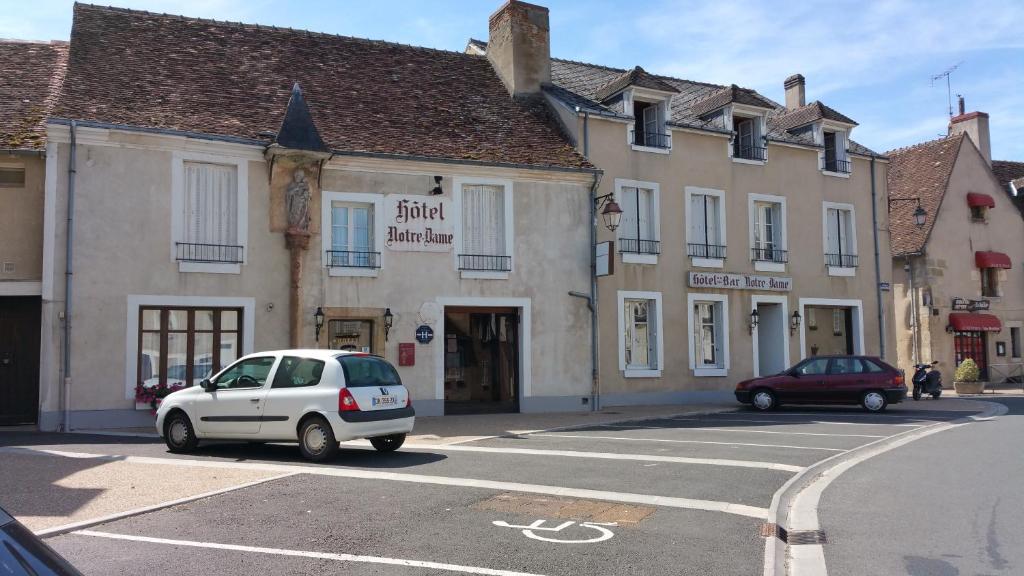 une petite voiture blanche garée devant un bâtiment dans l'établissement Hotel A Notre Dame, à La Châtre