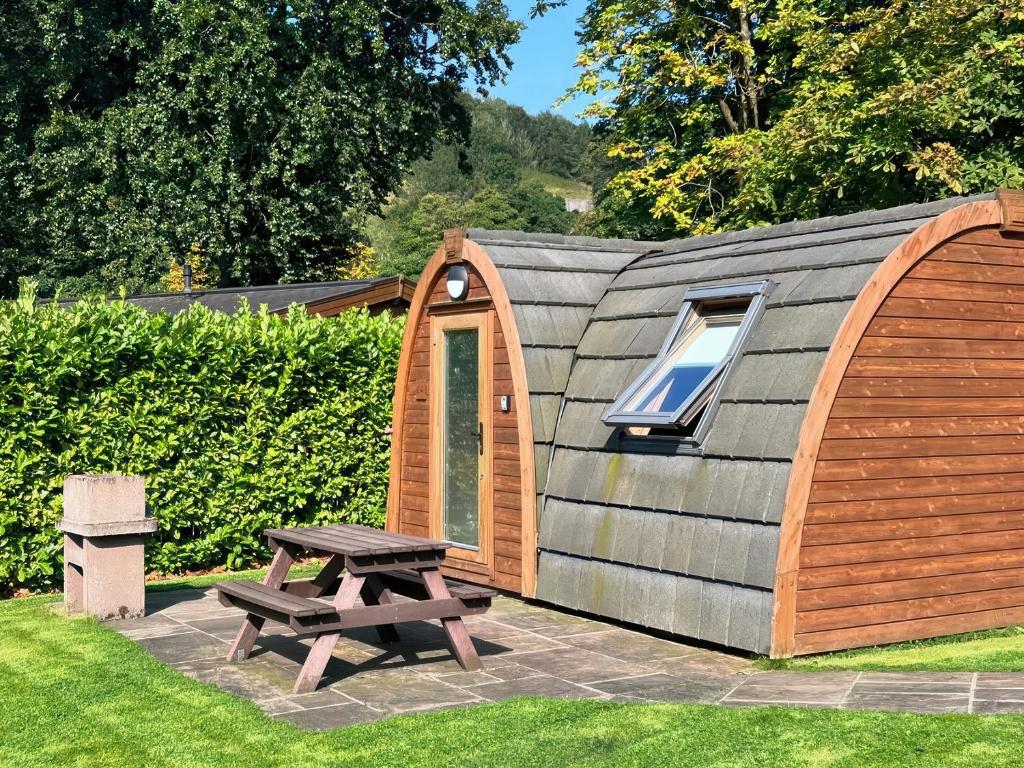 a small wooden cabin with a picnic table and a bench at Lakeside Pods - pet free in Oldham