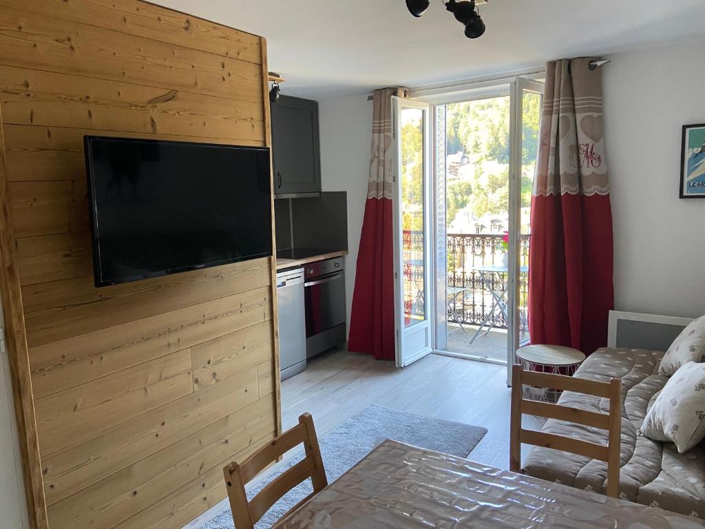 - un salon avec une télévision à écran plat sur un mur en bois dans l'établissement Appartement centre ville avec balcon, à Mont-Dore