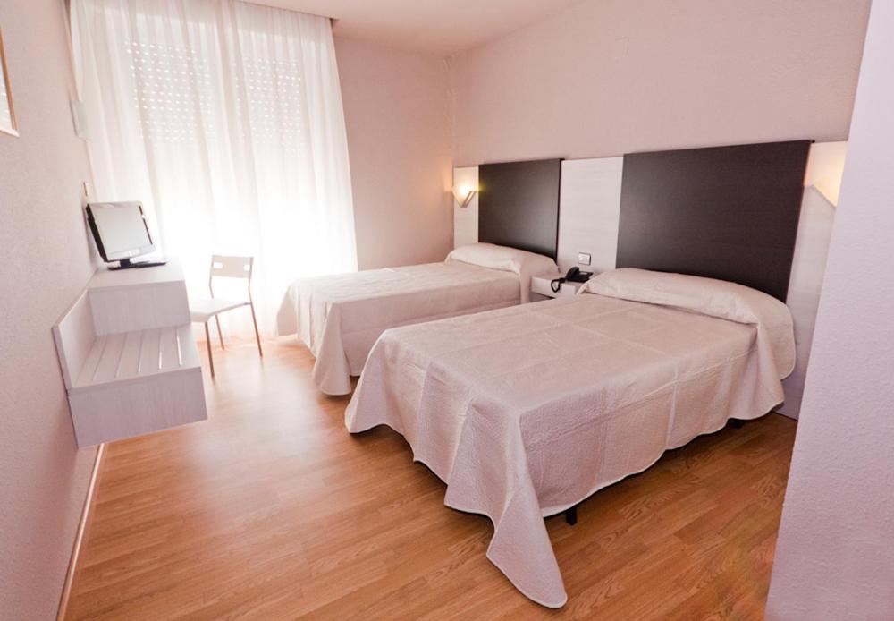 a hotel room with two beds and a television at Hotel Fornos in Calatayud