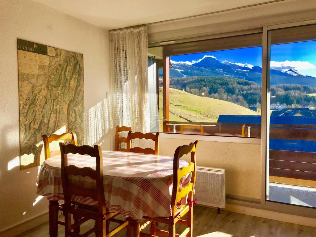 ein Esszimmer mit einem Tisch und einem großen Fenster in der Unterkunft Studio cabine avec vue sur montagne à Villard-de-Lans - FR-1-515-68 in Villard-de-Lans