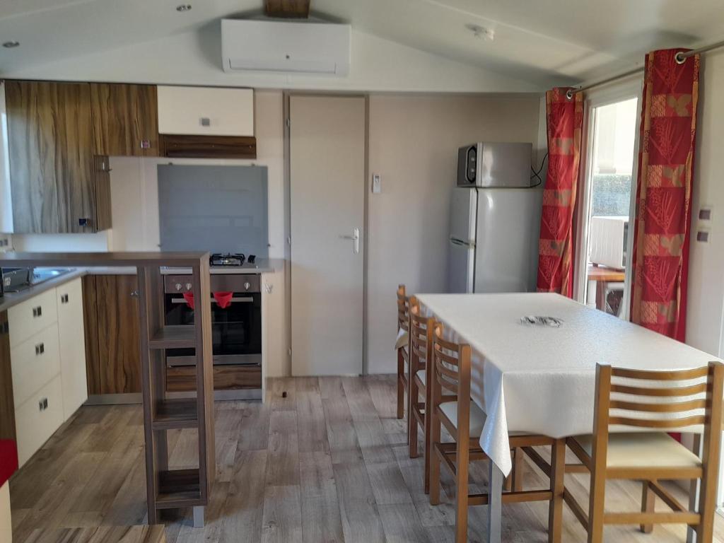 a kitchen with a table and chairs and a refrigerator at Mobil home camping les Charmettes 4 étoiles les MATHES en Charente Maritime prés du ZOO de la Palmyre 8 personnes tout confort 3 chambres 2salles de bains 2 WC Lave linge lave vaisselle Climatisation bien situé in Les Mathes