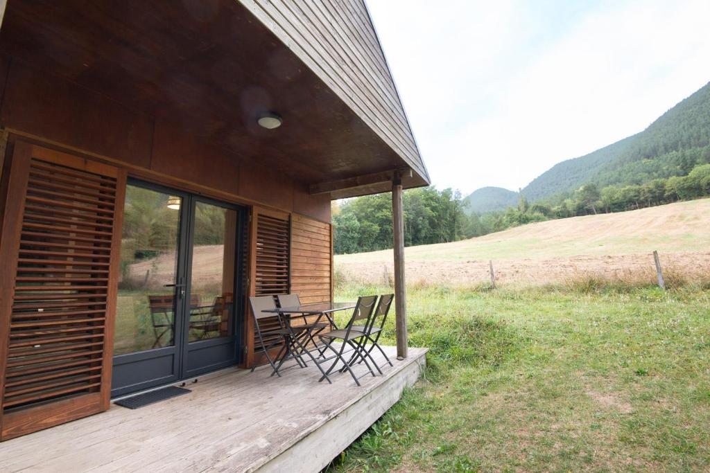 une terrasse couverte d'une maison avec une table et des chaises dans l'établissement Chalet 4 personnes - camping les berges du bramont, à Saint-Beauzile