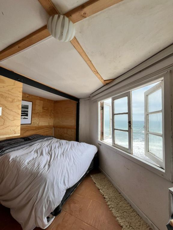 um quarto com uma cama e uma janela em El Barco Pichilemu em Pichilemu