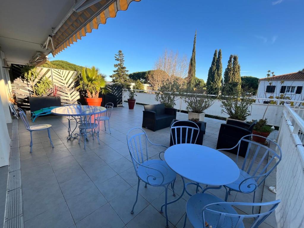 un patio avec tables et chaises sur un balcon dans l'établissement RDC GRANDE TERRASSE à 200m de la plage au calme, à Cavalaire-sur-Mer
