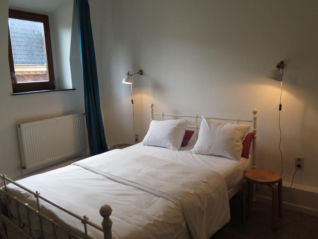a bedroom with a bed with white sheets and a window at Apartment Jules & Jim in Dinant