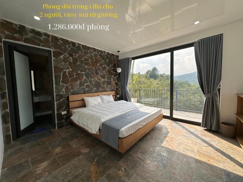 a bedroom with a bed and a large window at Ba Villa - Nhà của Hạnh Phúc in Ba Vì