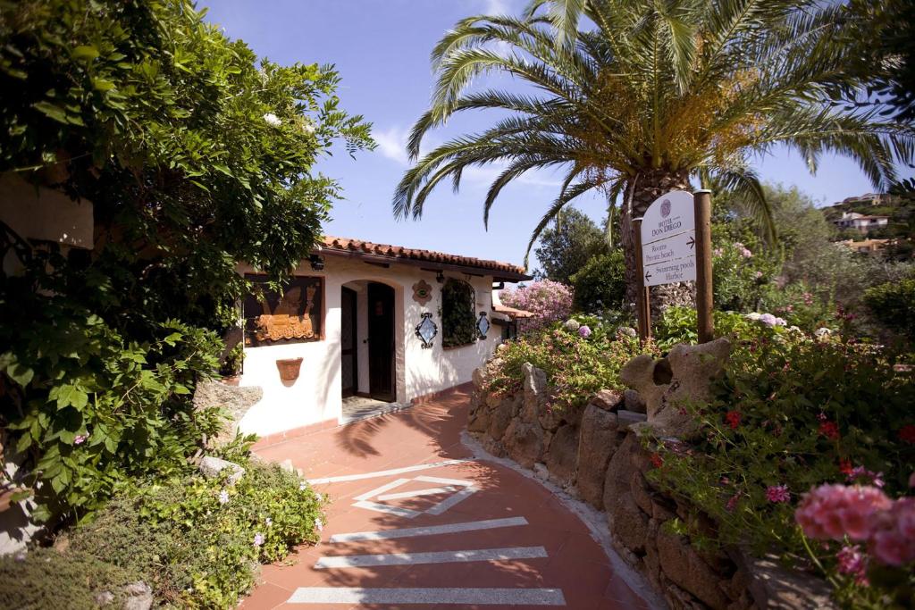 a house with a palm tree next to a walkway at Hotel Don Diego in Porto San Paolo