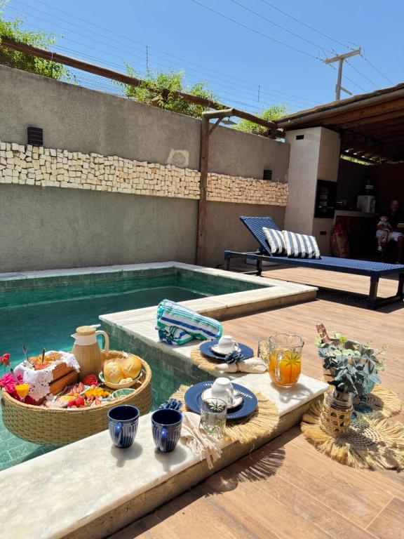 a table with food and drinks next to a swimming pool at Casa de Condomínio ao lado da Capela de Milagres in São Miguel dos Milagres
