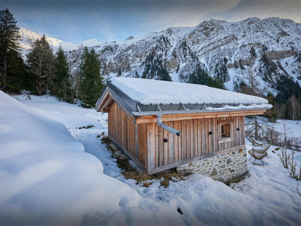 une petite cabine dans la neige avec des montagnes en arrière-plan dans l'établissement Petit Mazot La Chandelle - OVO Network, à Bionnassay