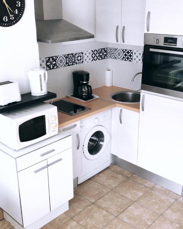 une cuisine avec des armoires blanches et une laveuse et une sécheuse dans l'établissement Le Bohème Charmant appartement meublé avec parking, à Amélie-les-Bains-Palalda