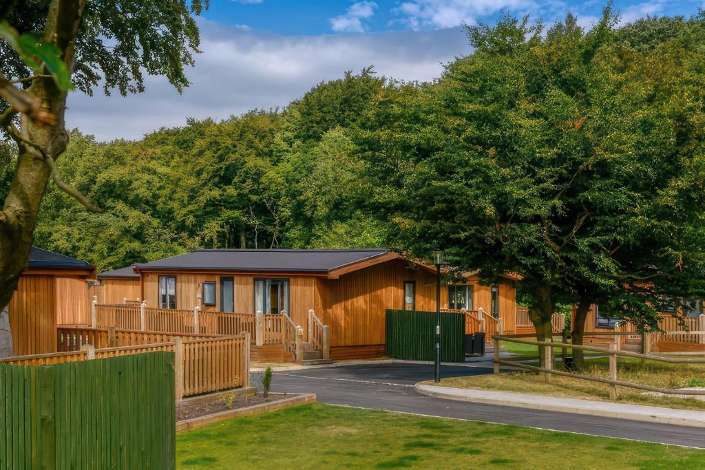 a row of lodges with a fence and trees at Dovestone Luxury Lodges sleeps 4 - pets welcome in Oldham