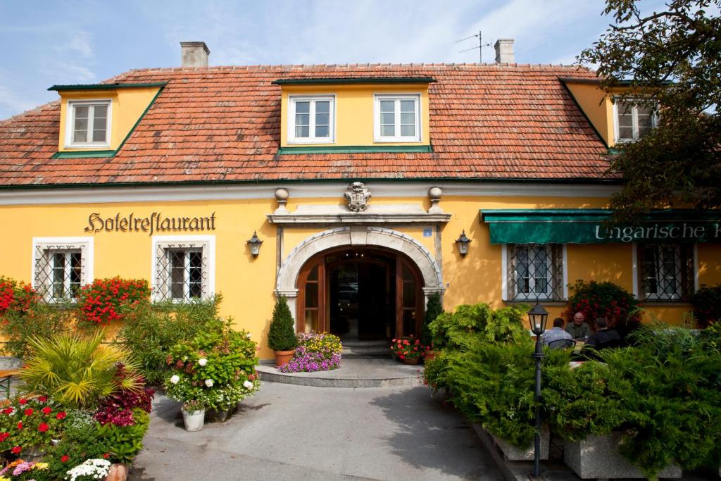 um edifício amarelo com um portão e flores à frente dele em Hotel Ungarische Krone em Bruckneudorf