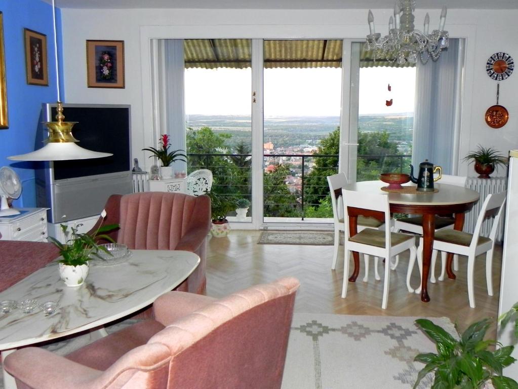 a living room with a table and chairs and a window at Tulipán Panoráma Apartman in Pécs