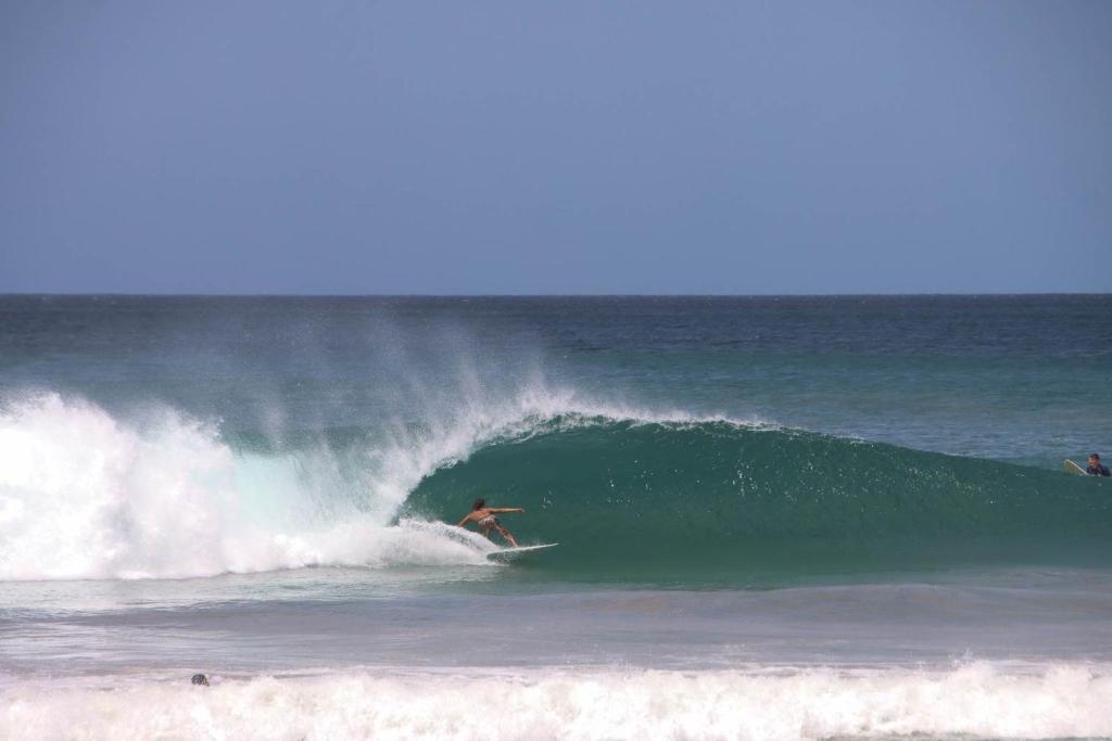 a man riding a wave on a surfboard in the ocean at Villa Serenity 6 bedroom - 1 minute to the beach in Santa Cruz