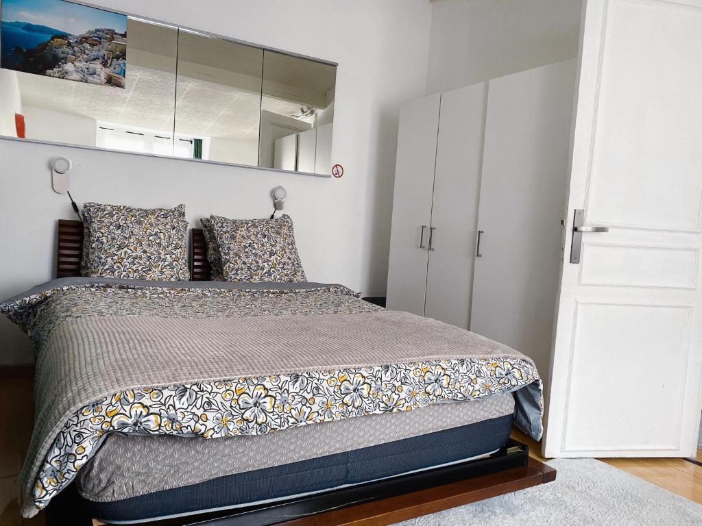 Un dormitorio con una cama grande y un espejo. en Appartement confort idéal visite Paris, en Ivry-sur-Seine