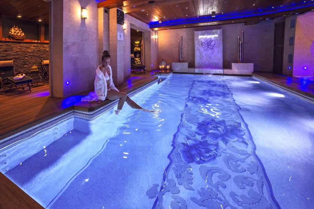 a woman sitting on the edge of a swimming pool at Mała Anglia - Boutique Apartments & SPA in Sopot