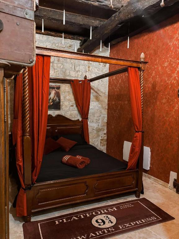 une chambre avec un lit à baldaquin avec des rideaux orange dans l'établissement Les sorciers de Lauzerte immersion magique, à Lauzerte