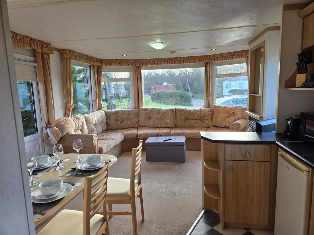 a living room with a couch and a table with chairs at Elf Wood Lodge - Swimming Spa, Sky Sports, Tennis, Hadrian's Wall listing in Port Carlisle