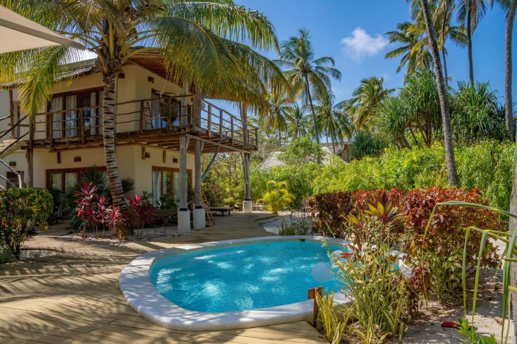 a villa with a swimming pool in front of a house at Zanzibar White Sand Luxury Villas & Spa - Relais & Chateaux in Paje