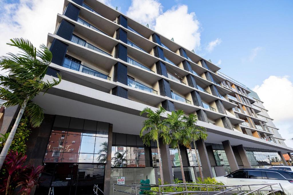 a building with palm trees in front of it at Oceânica Cabo Branco By Carpediem in Tambaú